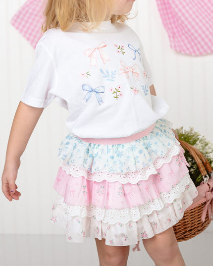 girl wearing white shirt with floral and bow watercolor design and floral skirt