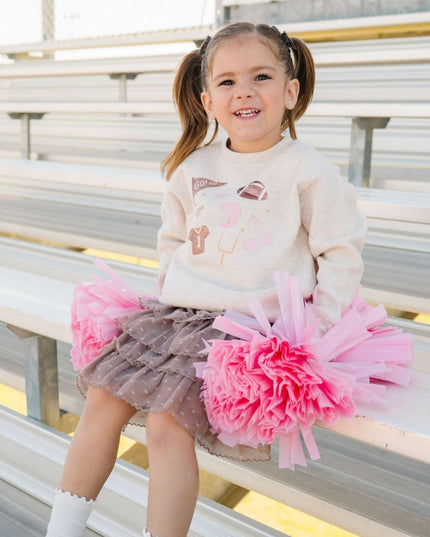 Girl wearing sweatshirt with football related icons and brown tutu