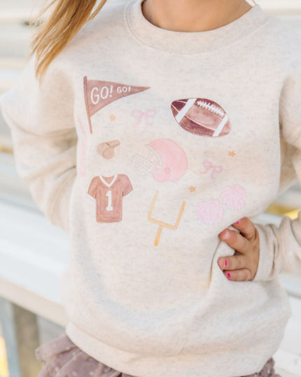 Girl wearing sweatshirt with football related icons and brown tutu