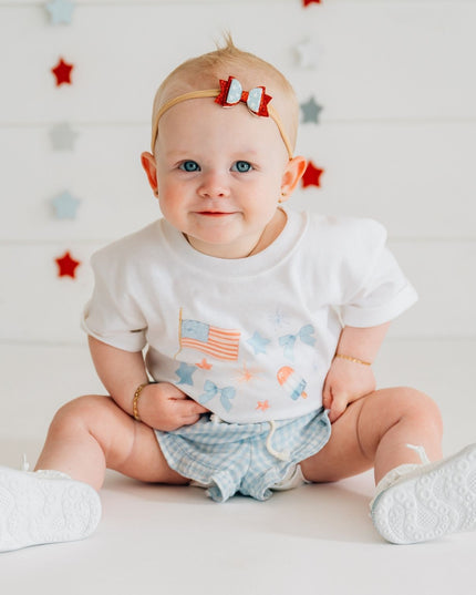 Baby wearing white baby romper with red, white and blue graphic