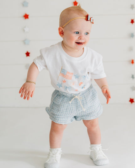 Baby wearing white baby romper with red, white and blue graphic