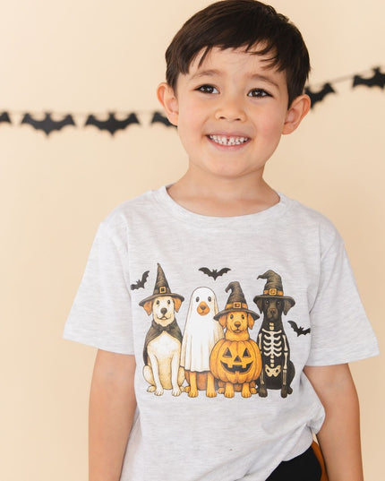 A young boy smiling and wearing a light gray heather t-shirt with a graphic of four dogs dressed in Halloween costumes 