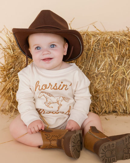 Baby wearing romper with 'horsin' around' graphic