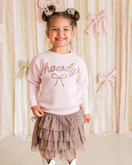 Girl wearing pink 'howdy' sweatshirt and brown skirt