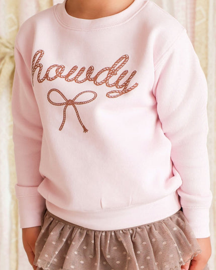 Girl wearing pink 'howdy' sweatshirt and brown skirt