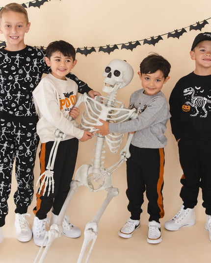 Four children wearing coordinated Halloween outfits pose with a toy skeleton 