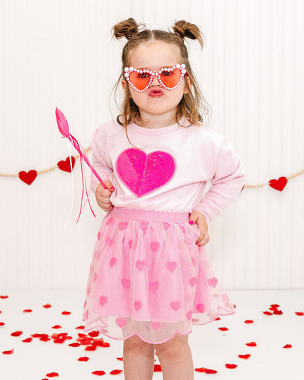 Girl wearing pink heart sweatshirt and tutu with sequin hearts