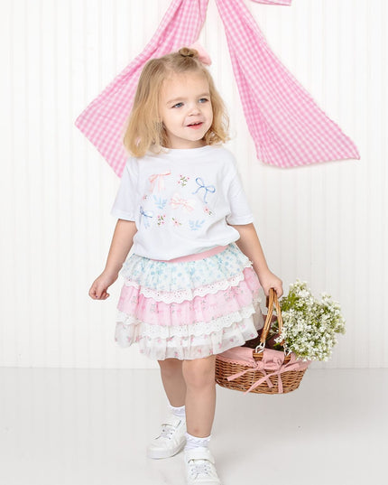 girl wearing white shirt with floral and bow watercolor design and floral skirt