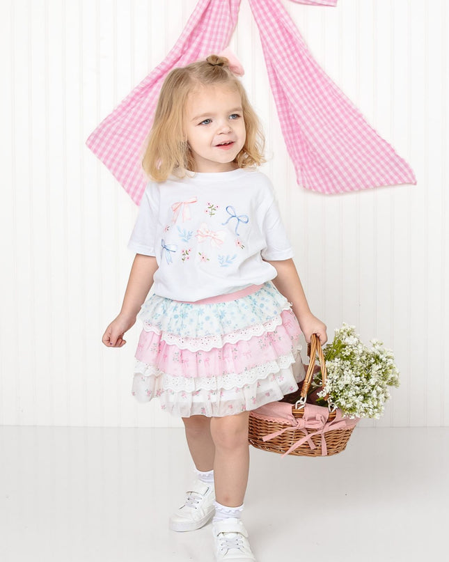 girl wearing white shirt with floral and bow watercolor design and floral skirt