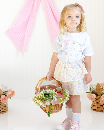 girl wearing white shirt with floral and bow watercolor design and floral skirt
