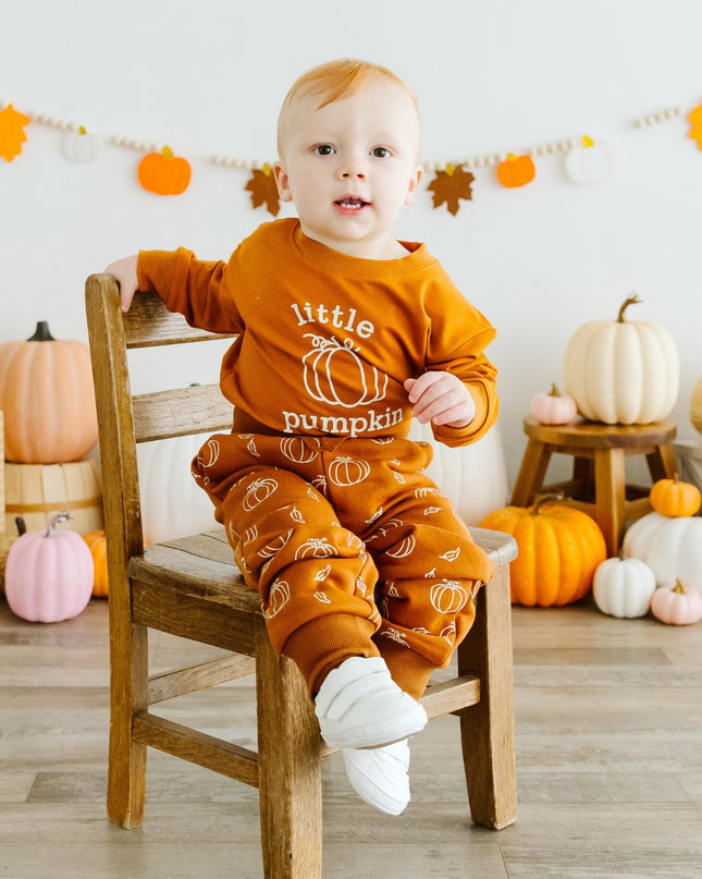 Baby wearing orange baby romper with 'little pumpkin' graphic and pumpkin sweatpants