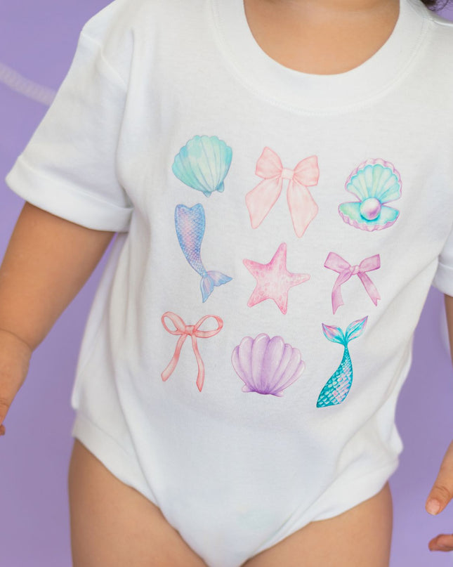 Baby wearing white romper with mermaid graphics