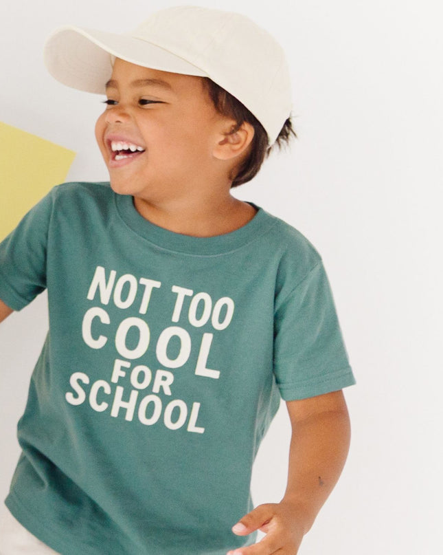 Boy wearing 'not too cool for school' green t-shirt