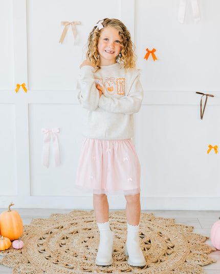 Young girl wearing a pink tutu and pumpkin sweatshirt