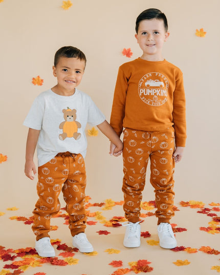 Two children wearing matching pumpkin-themed outfits 