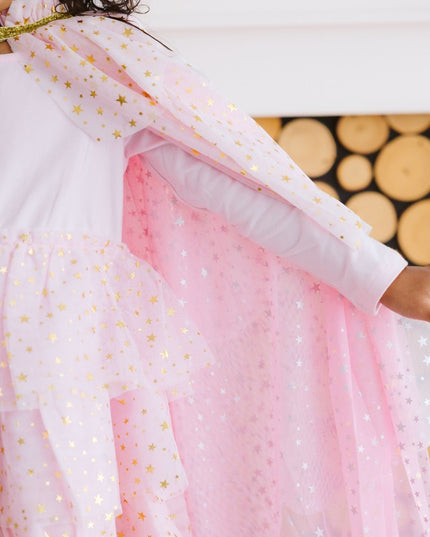 Girl wearing light pink tutu dress and cape with gold stars 