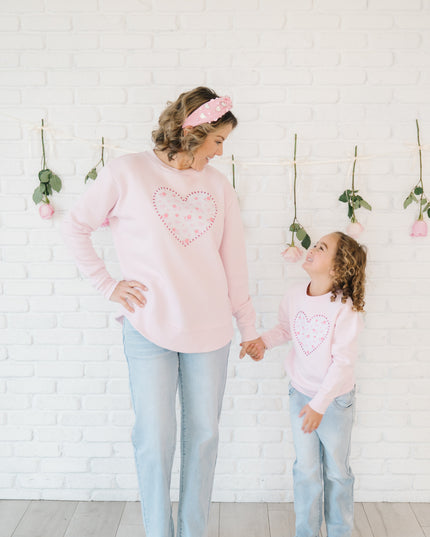 Mother and daughter wearing matching pink sweatshirts with floral and pearl heart patches
