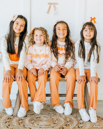 four kids wearing matching outfits with pumpkins.