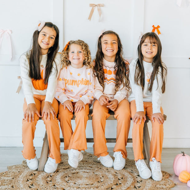 four kids wearing matching outfits with pumpkins.