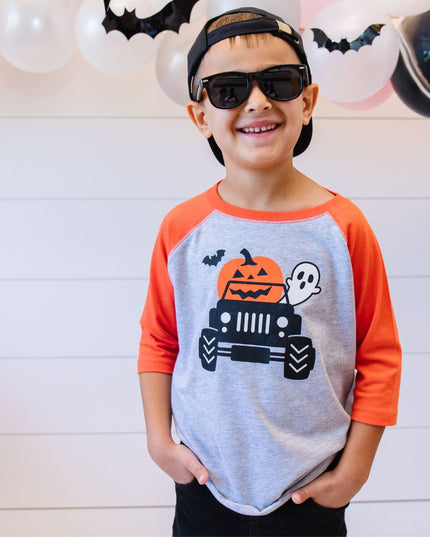 Boy wearing Halloween T-shirt with truck, pumpkin, ghost and bat graphic and sunglasses