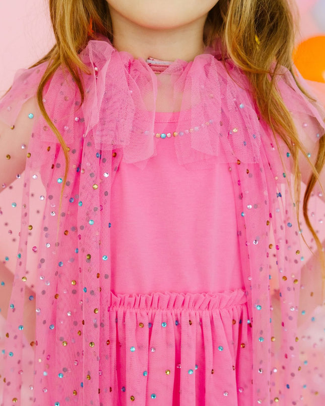 Girl wearing pink dress and pink tulle cape with multicolor rhinestones