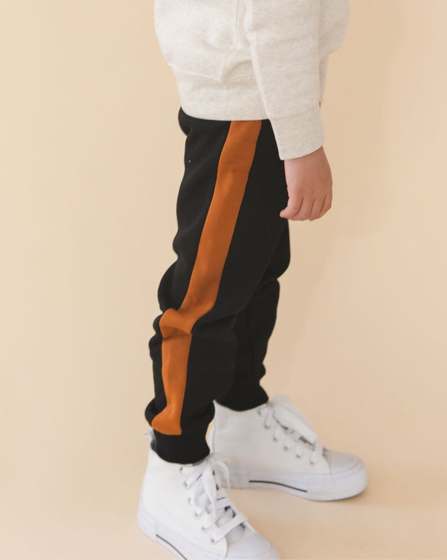 Boy wearing black jogger pants with burnt orange  side stripes