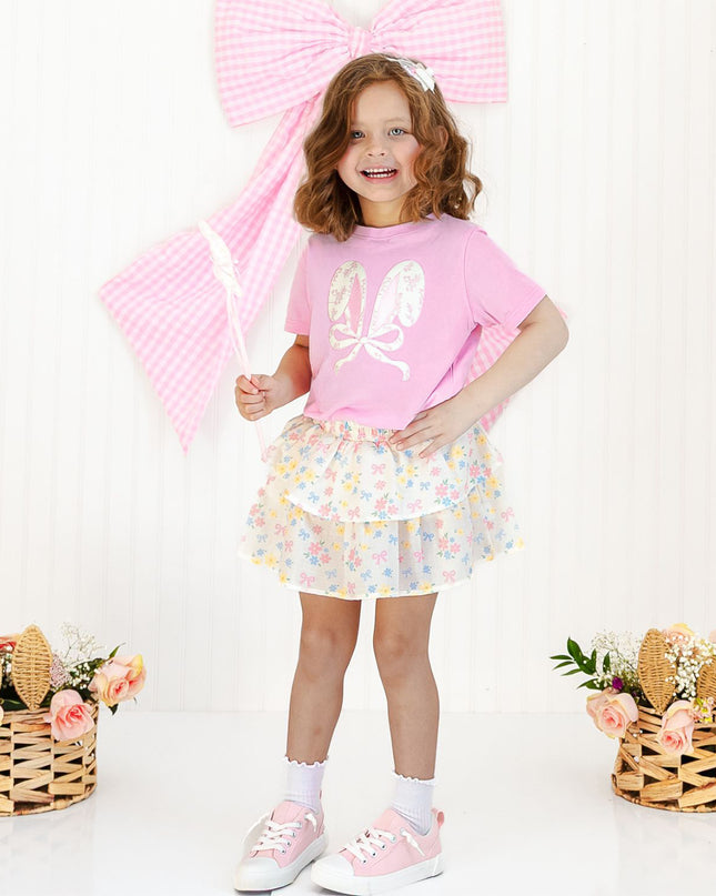 Girl wearing pink t-shirt with lace bow bunny ears patch and floral skirt