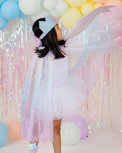 A young girl posing in a sparkly lavender-blue cape and matching tiara
