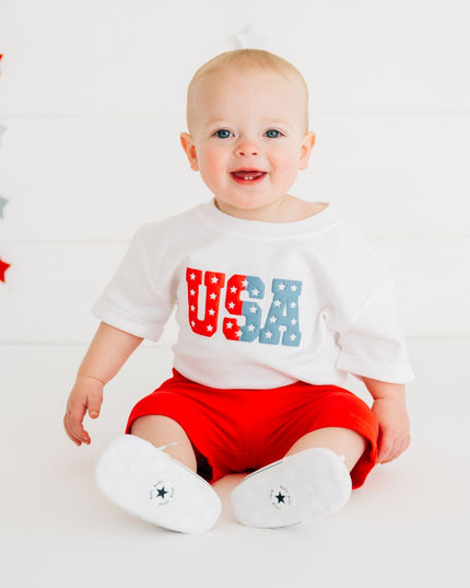 Baby wearing white romper with USA graphic