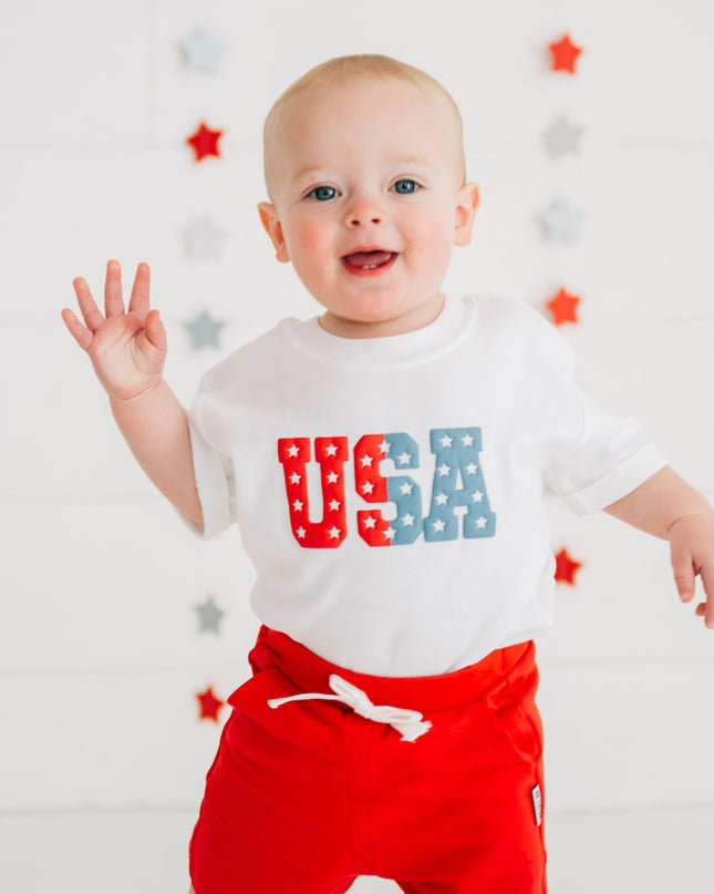 Baby wearing white romper with USA graphic
