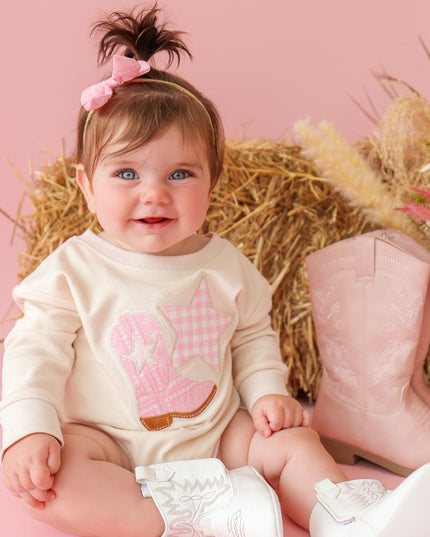 Baby wearing romper with cowboy boot and star patch