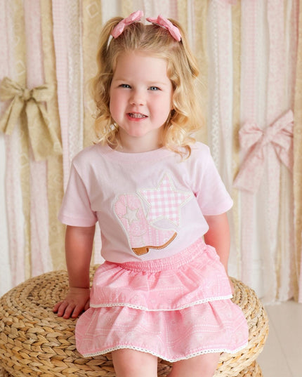 Girl wearing pink t-shirt with cowboy boot and star patch and bandana skirt