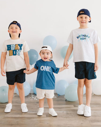Three children wearing birthday outfits