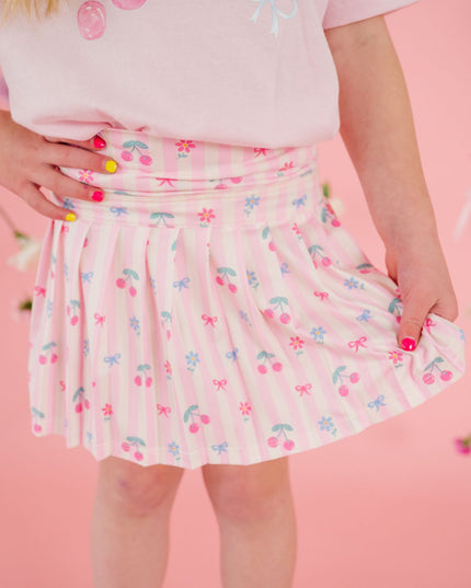 Girl wearing pink and white striped skort with cherries and bows