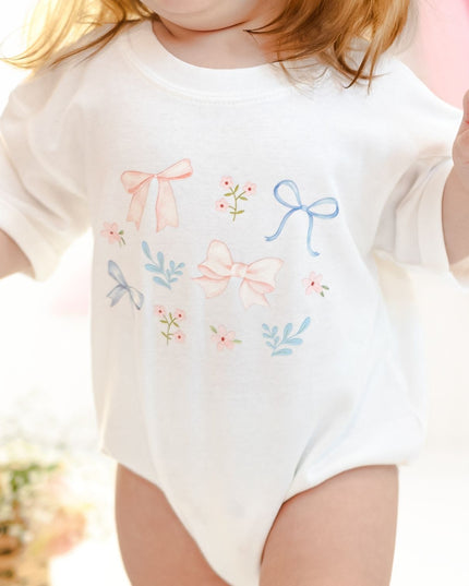 Baby wearing white shirt with floral and bow watercolor design 
