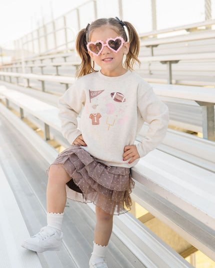 Girl wearing sweatshirt with football related icons and brown tutu