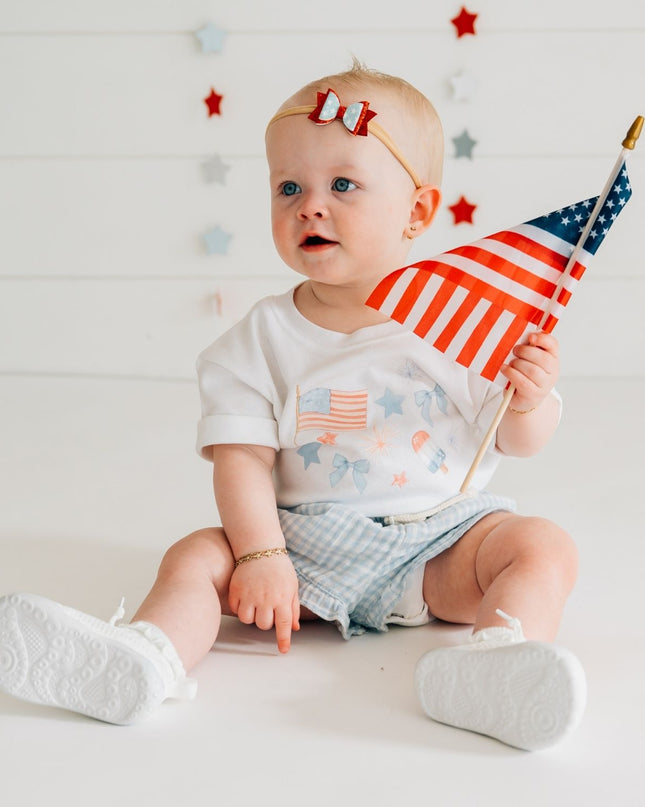Baby wearing white baby romper with red, white and blue graphic