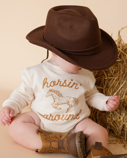 Baby wearing romper with 'horsin' around' graphic