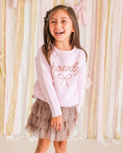 Girl wearing pink 'howdy' sweatshirt and brown skirt