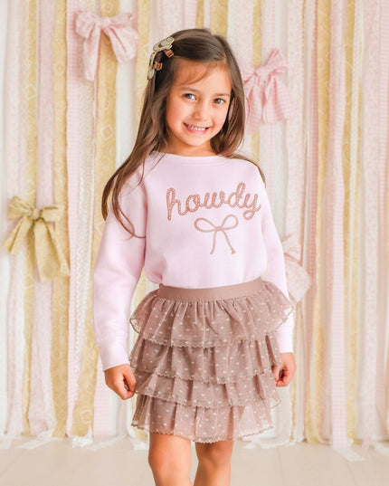 Girl wearing pink 'howdy' sweatshirt and brown skirt
