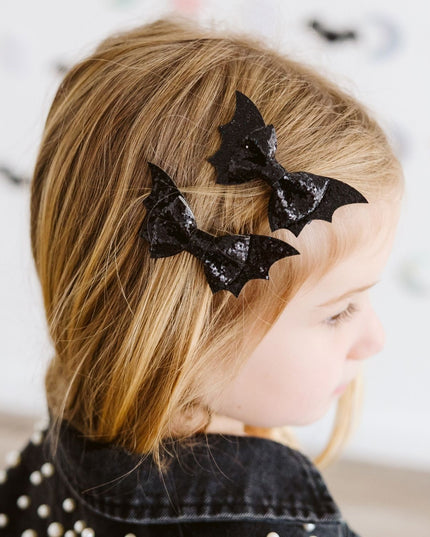 Girl wearing Black glittery bat bow hair clips 