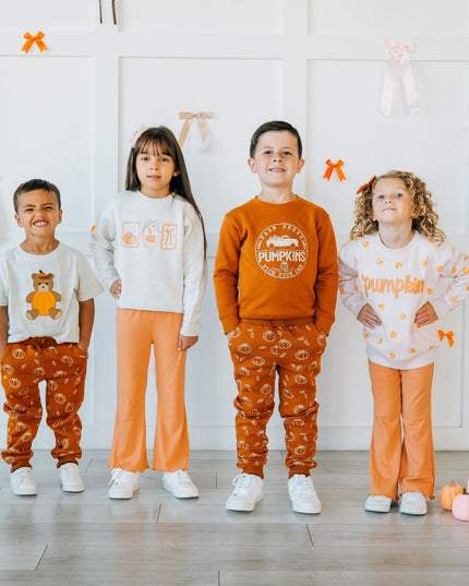 four kids wearing matching outfits with pumpkins.