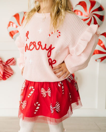 Girl wearing red tutu with red and white sequin candy canes and bows and pink merry sweater 