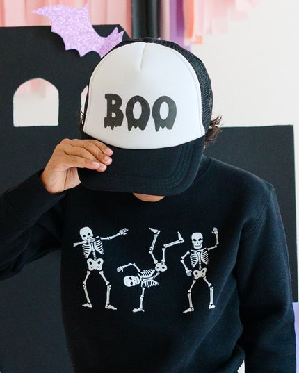 Boy wearing Black Sweatshirt with dancing skeletons and "boy" trucker hat