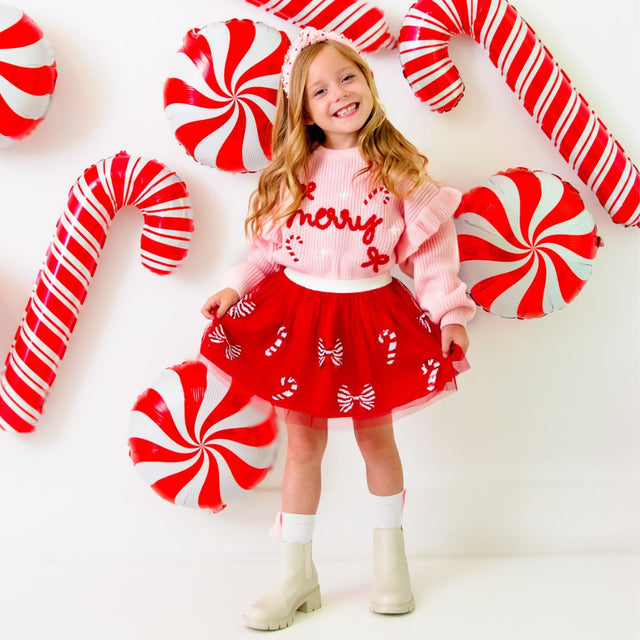 Girl wearing red tutu with red and white sequin candy canes and bows and pink merry sweater 