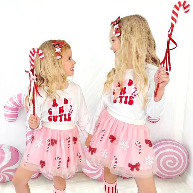 two girls wearing Christmas outfits holding candy cane Christmas wands