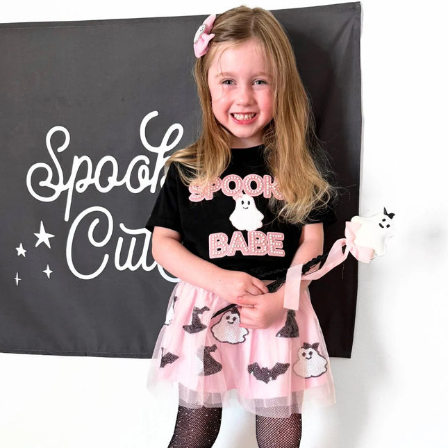 Girl wearing Black t-shirt with spooky babe and ghost patch and pink tutu with ghosts and bats holding ghost wand