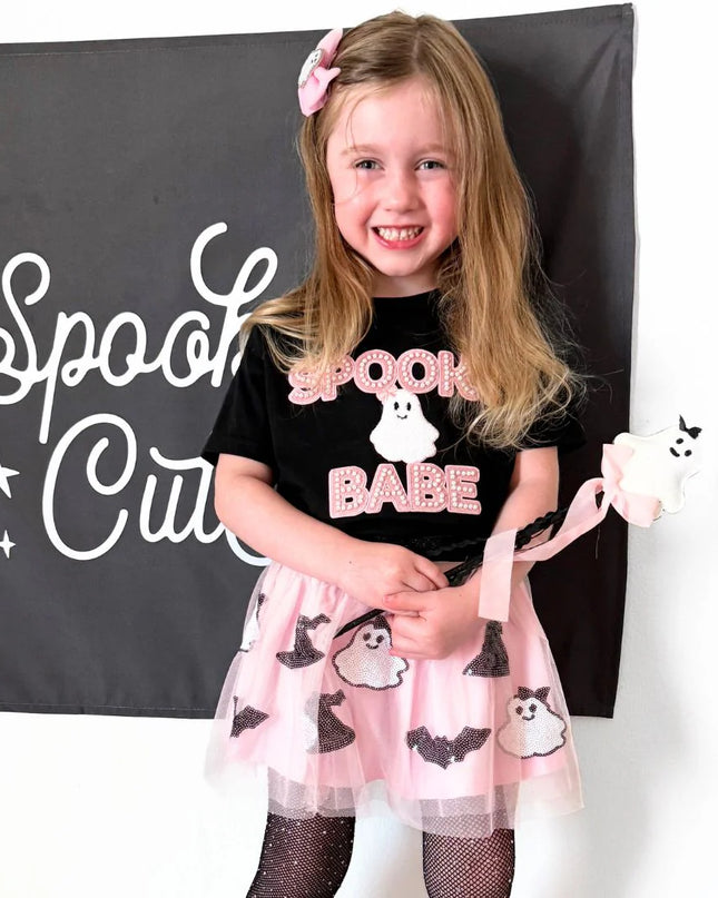 Girl wearing Black t-shirt with spooky babe and ghost patch and pink tutu with ghosts and bats holding ghost wand