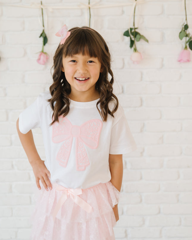 Girl wearing white t-shirt with pink lace bow 
