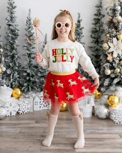 Girl wearing holly jolly Christmas sweatshirt, red reindeer tutu and holding a reindeer wand